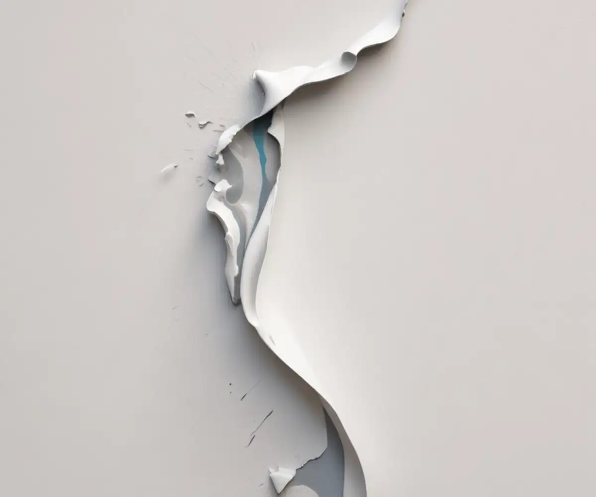 Close-up of a white wall with a large section of paint peeling away in a flexible, rubbery sheet, revealing the underlying surface.